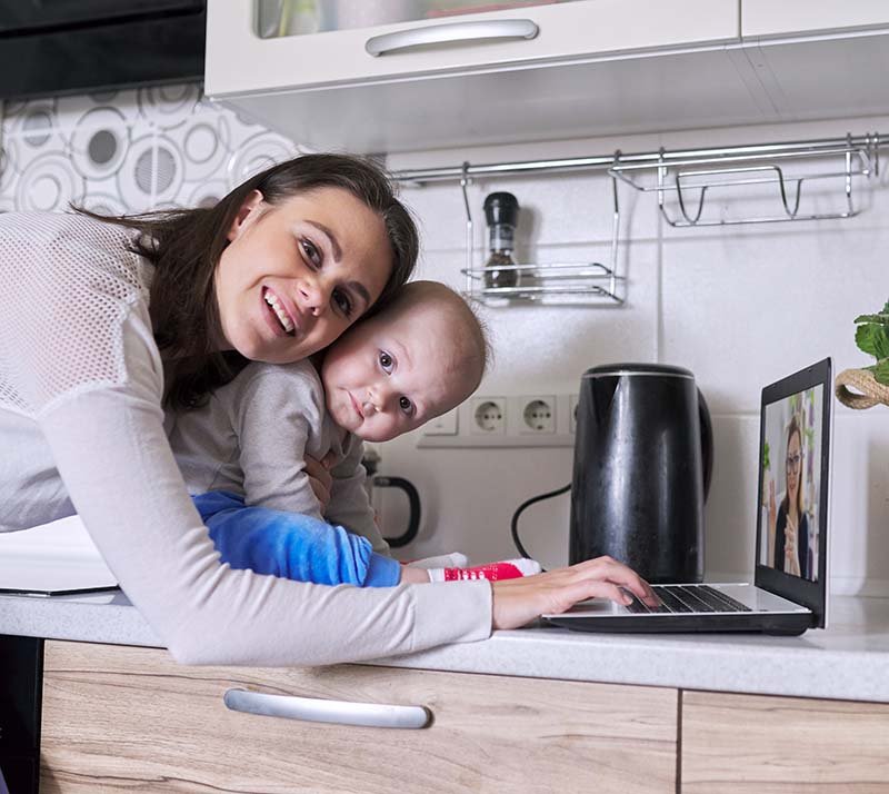 Young mother with toddler in her arms talking online with psychologist, making video call, video conference using laptop at home. Technology, mental health, therapy, distance lifestyle concept